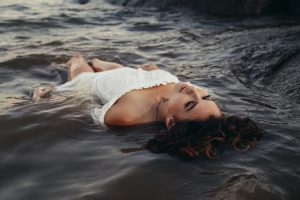 Woman in white dress floating on her back in water