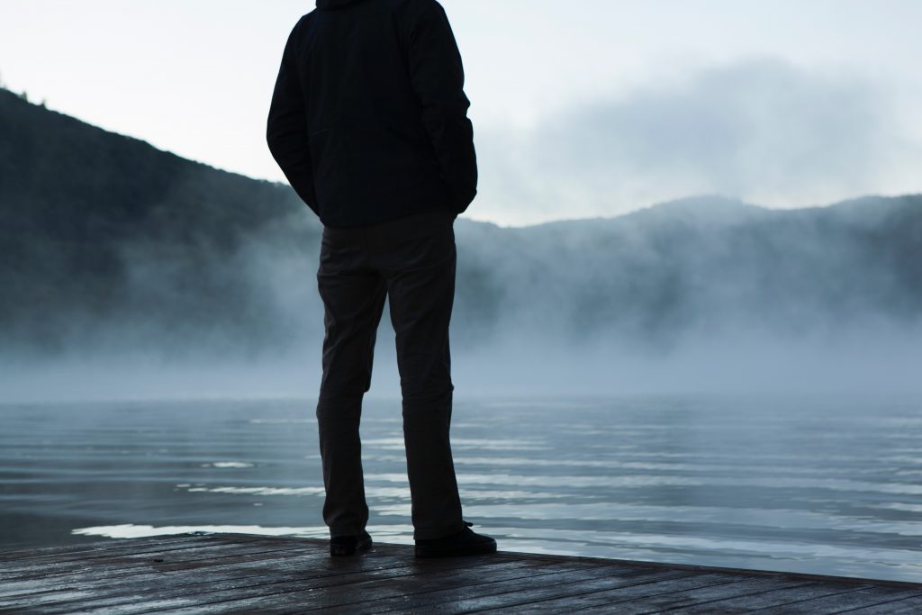 Man standing alone on a dock, in silhouette